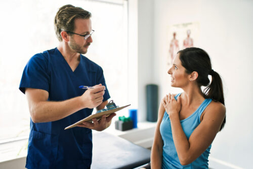 Fizjoterapeuta przeprowadza wywiad z pacjentką na pierwszej wizycie w gabinecie fizjoterapii