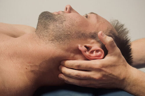 Fizjoterapeuta robi pacjentowi masaż bolącej szyi