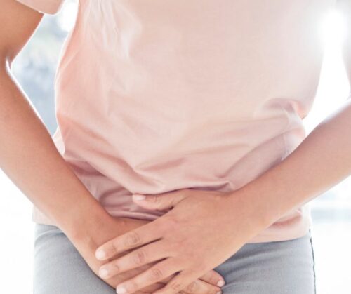 Osoba trzyma ręce w okolicy miednicy