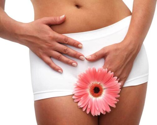 Kobieta w białych spodenkach trzyma ręce w okolicy dna miednicy