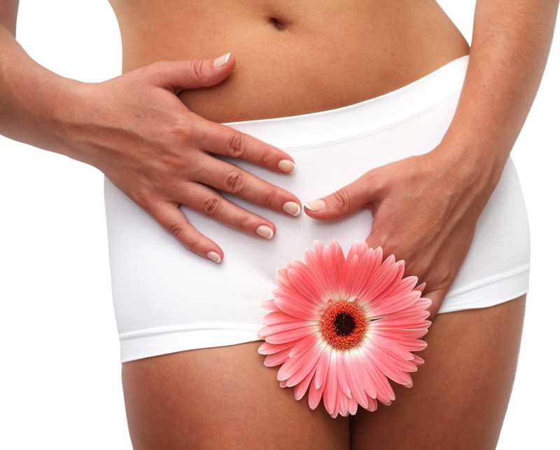 Kobieta w białych spodenkach trzyma ręce w okolicy dna miednicy