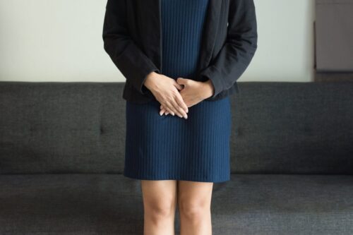 Kobieta stoi i trzyma ręce w okolicy miednicy