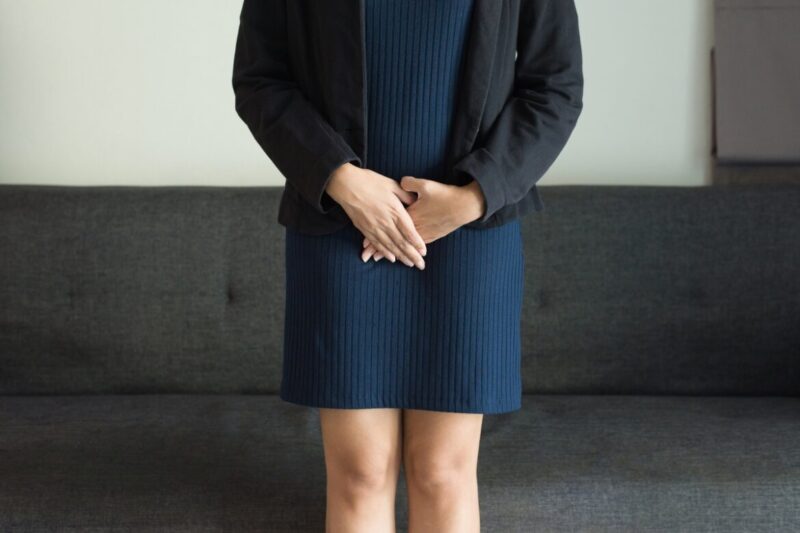 Kobieta stoi i trzyma ręce w okolicy miednicy