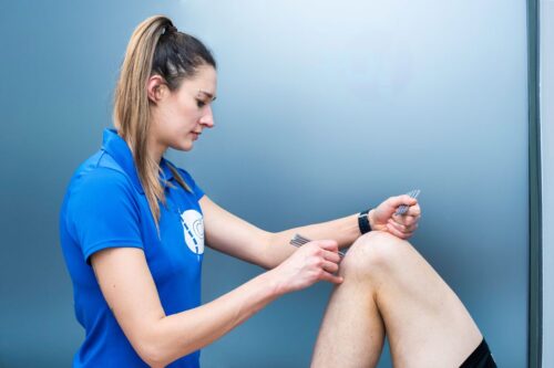 Fizjoterapeutka przeprowadza pinoterapię kolana