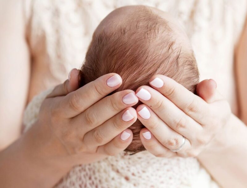Kobieta podtrzymuje główkę noworodka