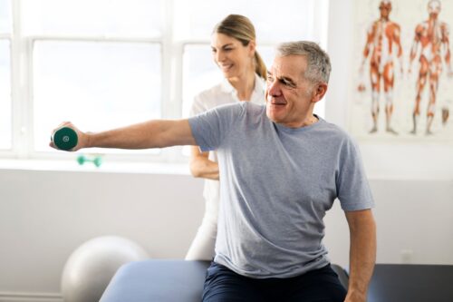 Rehabilitantka przeprowadza rehabilitacje starszego mężczyzny